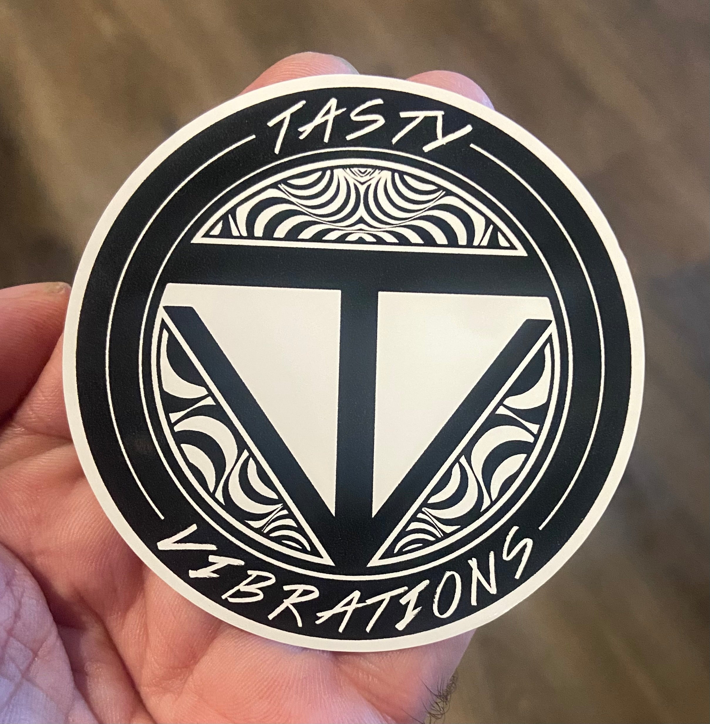 Circular sticker with 'Tasty Vibrations' design held in a hand against a blurred background